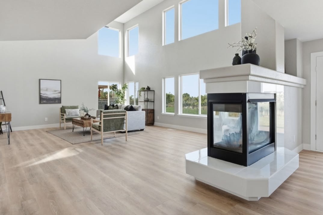 Bright great room with a two-sided fireplace and tall windows