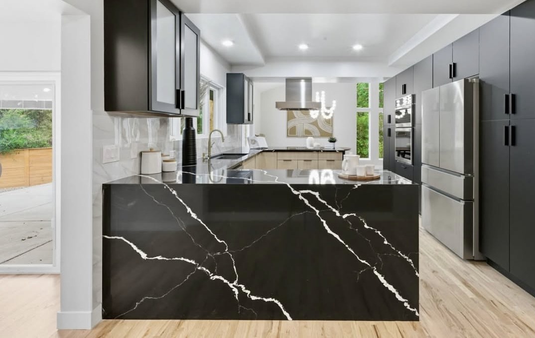 Modern kitchen with a black marble waterfall island and dark cabinets