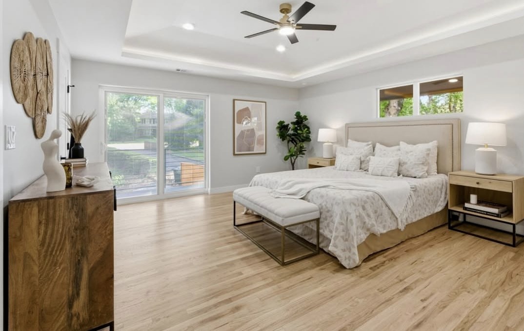 Primary bedroom with a tray ceiling and wood floors