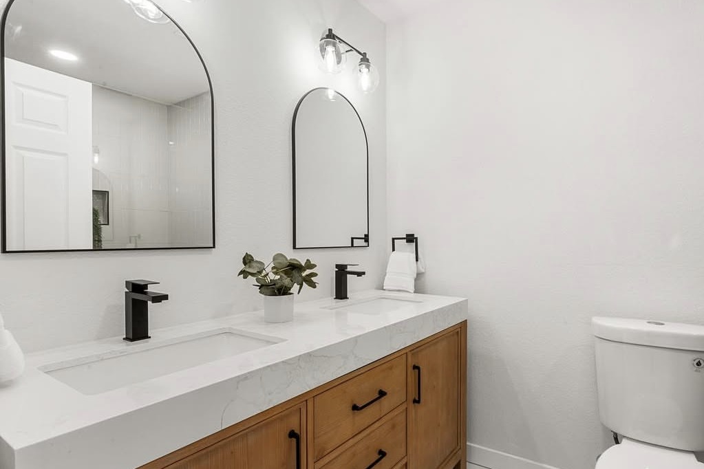 Bathroom with a wood double vanity and arched mirrors