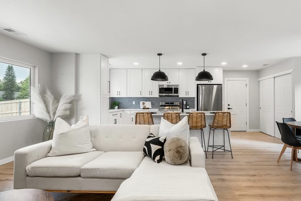 Open living room and white kitchen with black pendant lights