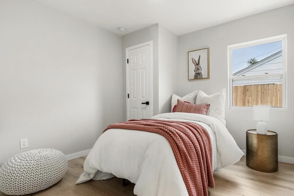 Bedroom with a coral throw and woven pouf