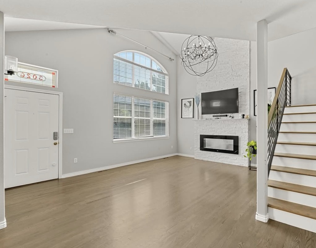 Bright living room with arched window, linear fireplace and open staircase in Aurora, CO