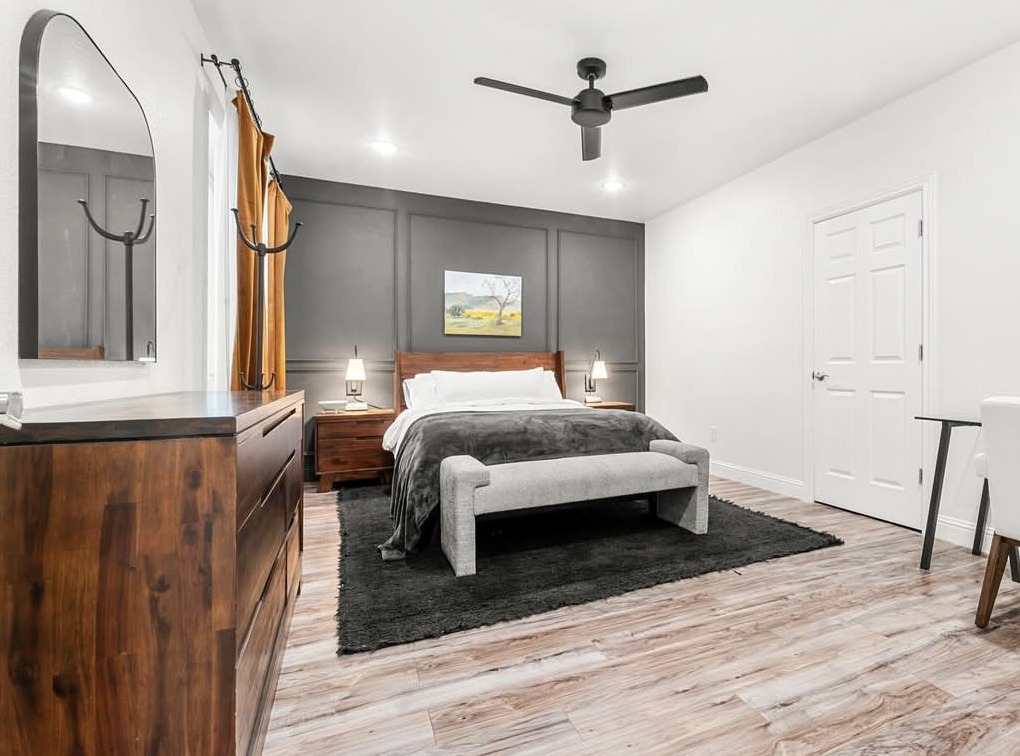 Bedroom with dark paneled accent wall and walnut furniture in Aurora, CO