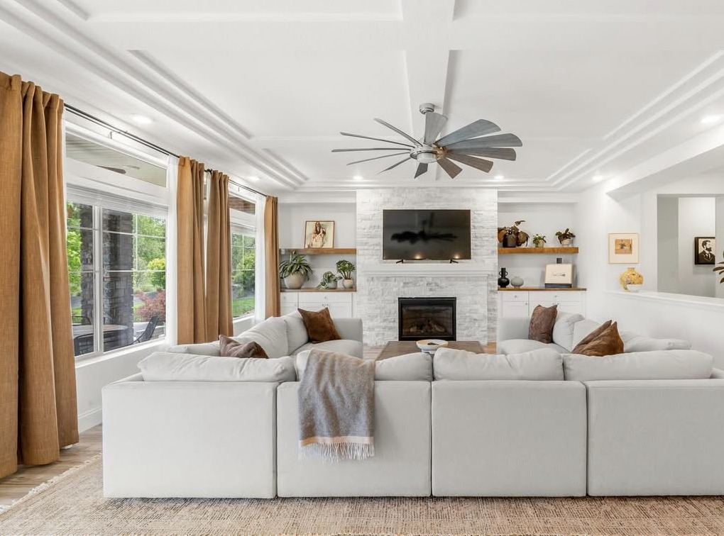 Living room with stacked-stone fireplace and windmill ceiling fan in Aurora, CO