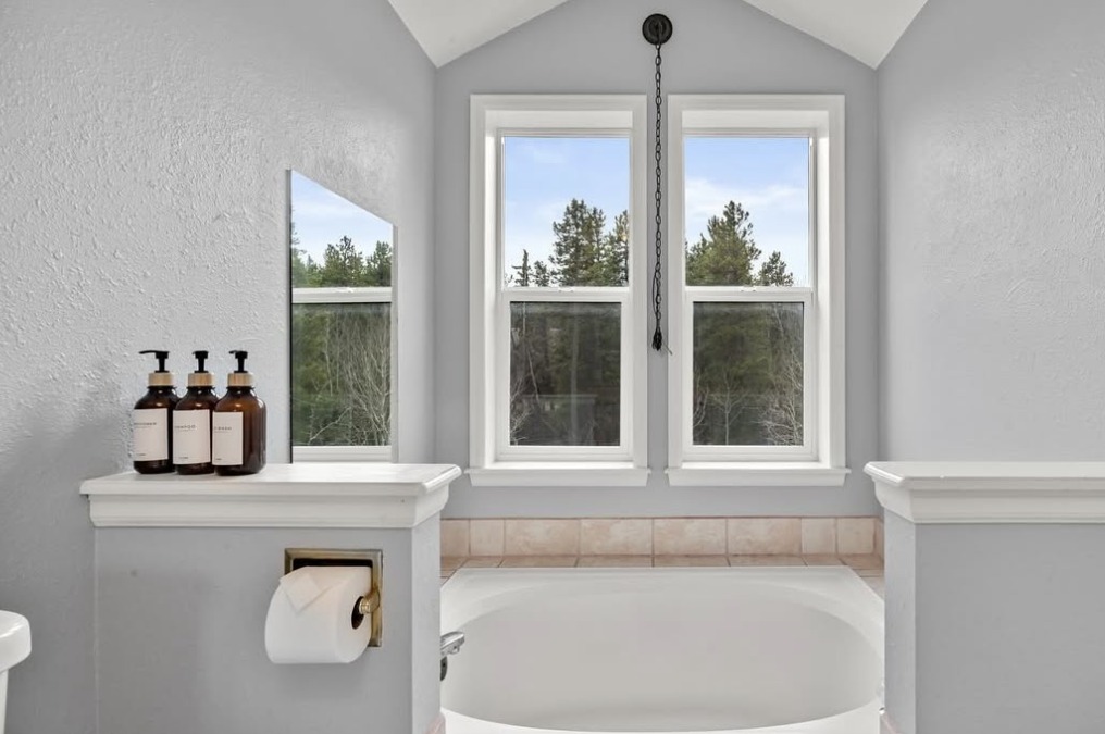 Bathroom soaking tub under twin windows with pine views in Black Hawk, CO