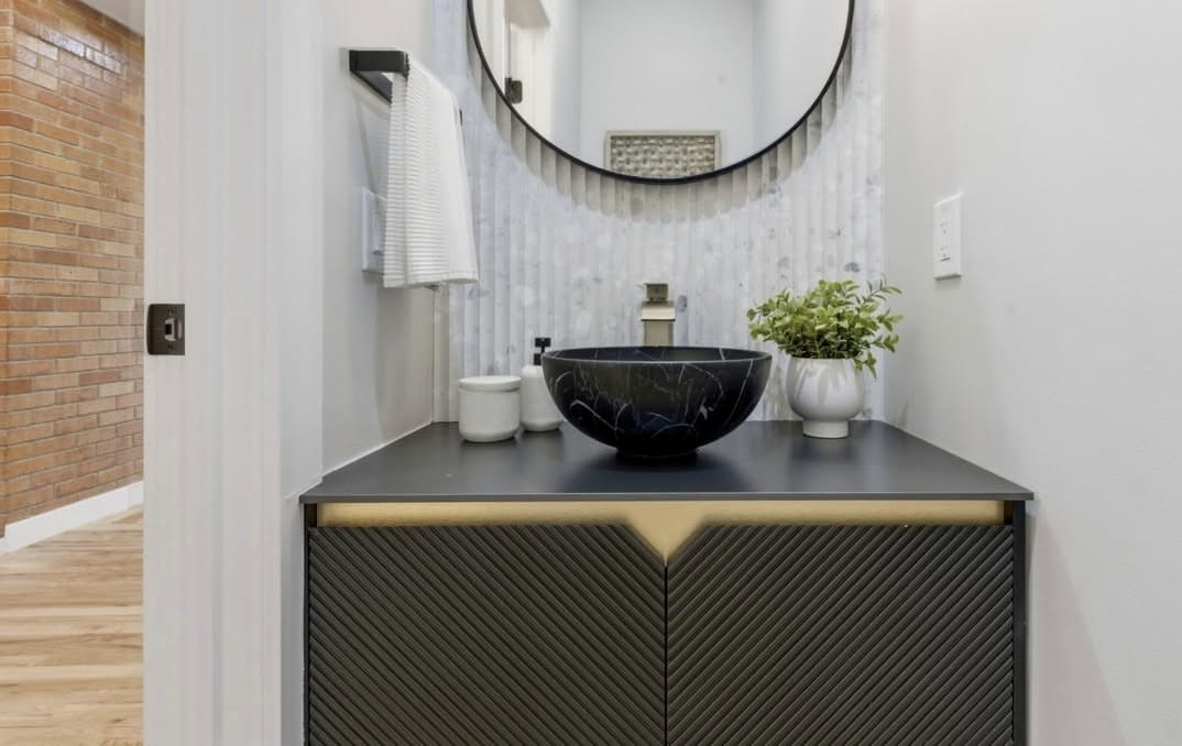 Powder room with a vessel sink and round mirror