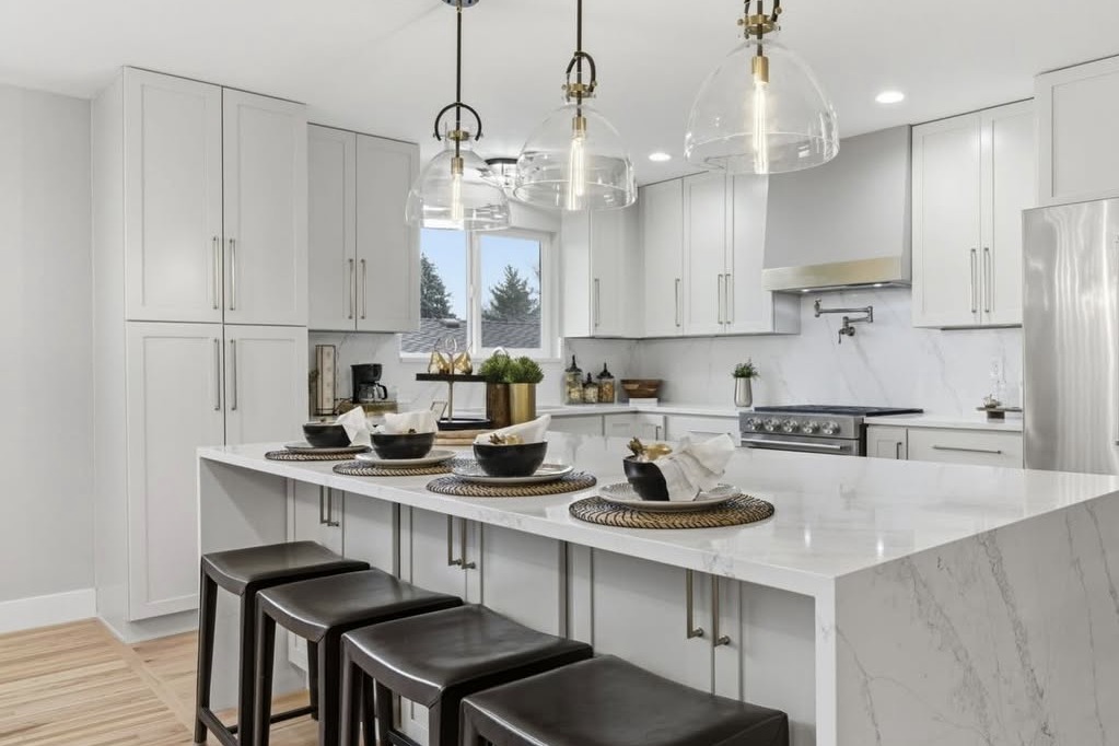 White kitchen with a waterfall island and glass pendant lights