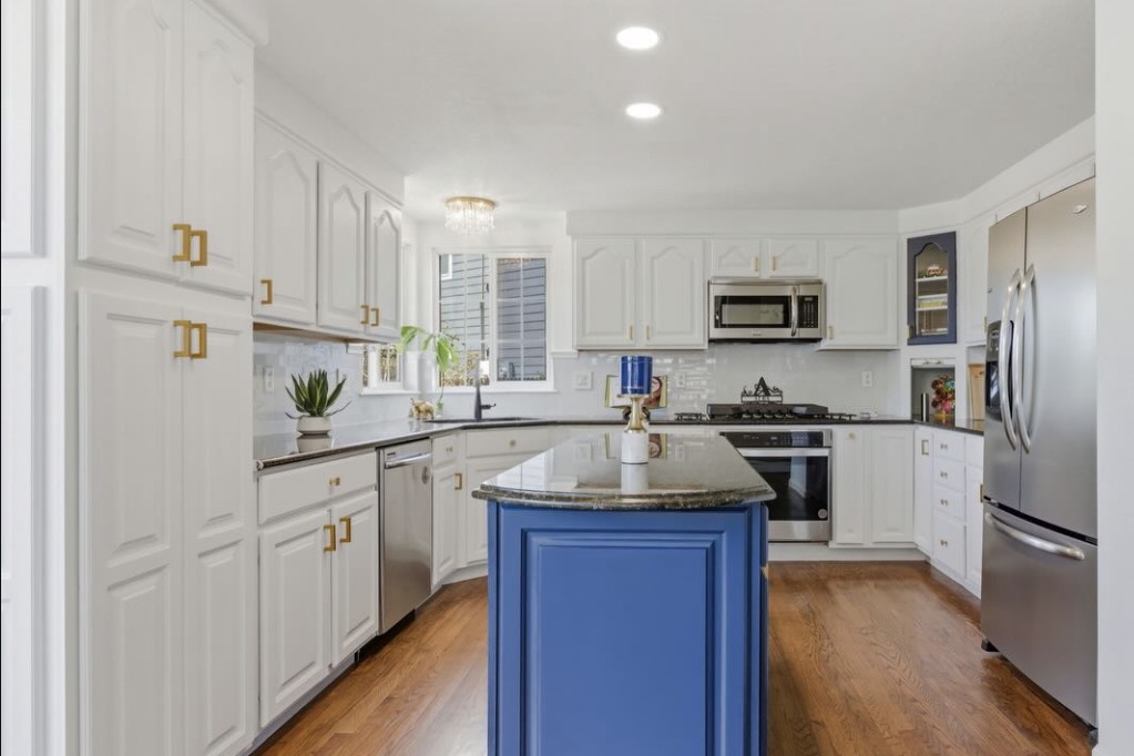 White kitchen with a blue island and hardwood floors