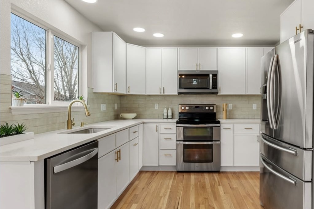 White kitchen with gold faucet and hardwood floors