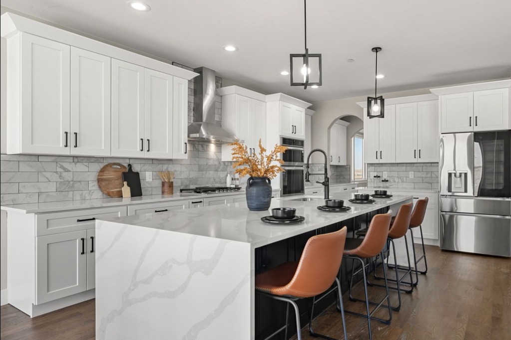 White kitchen with a marble waterfall island and leather barstools