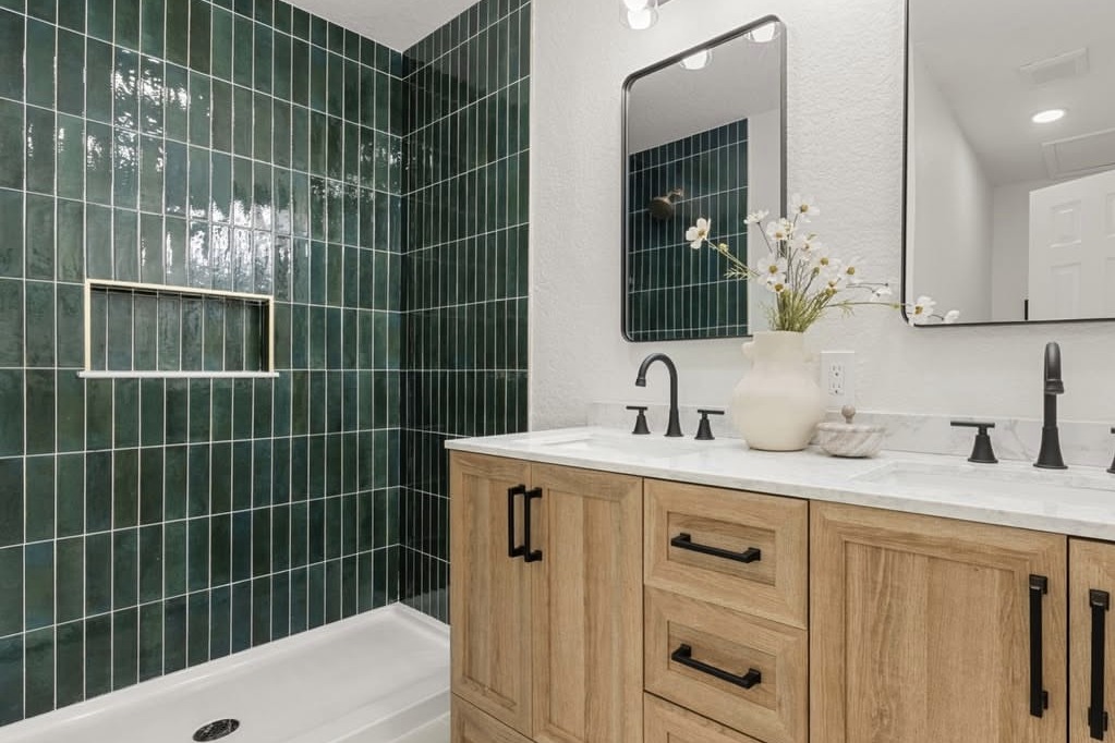 Bathroom with green tile and a wood double vanity