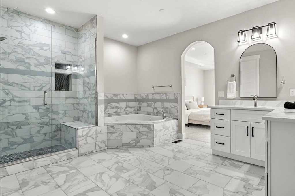 Marble primary bathroom with a corner tub and walk-in shower