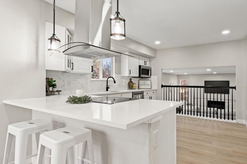 White kitchen peninsula with a range hood and loft view