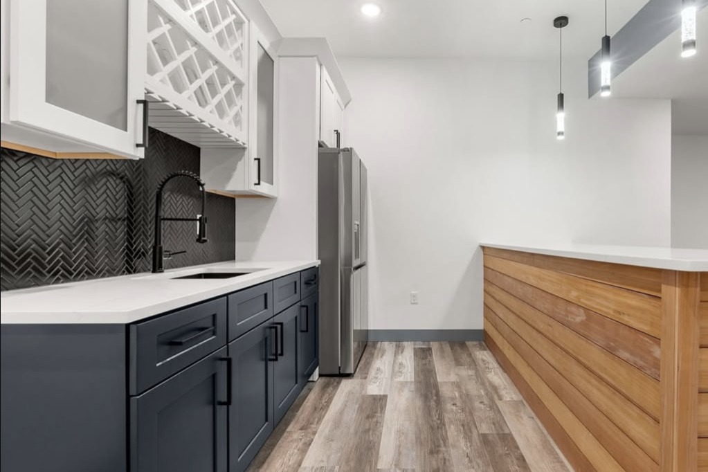 Basement wet bar with navy cabinets and a wine rack