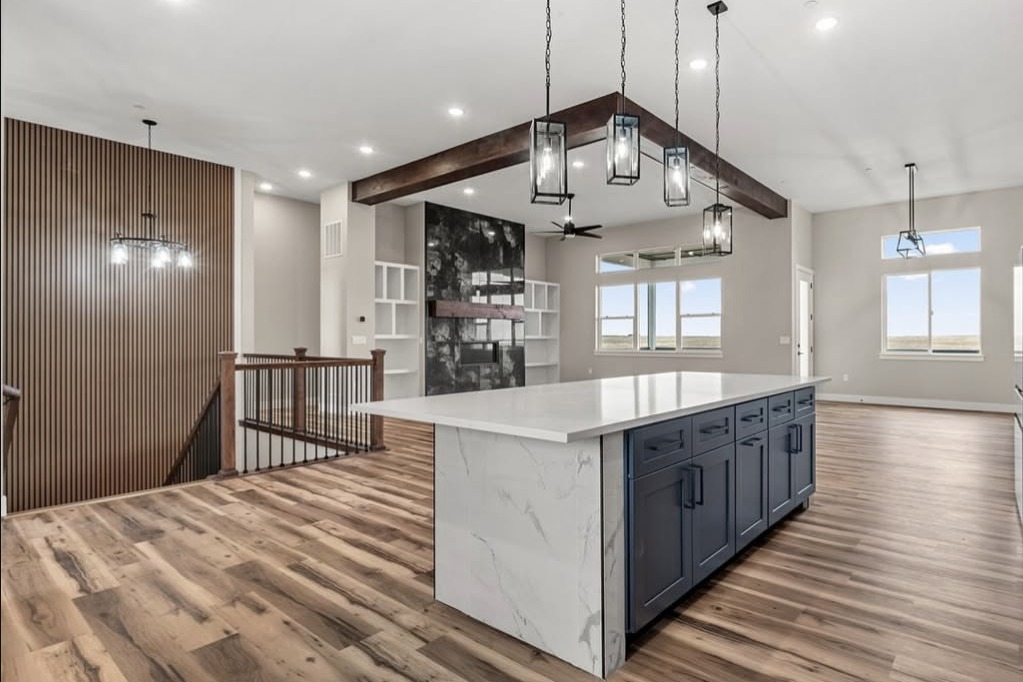 Open great room with a navy island and wood beams