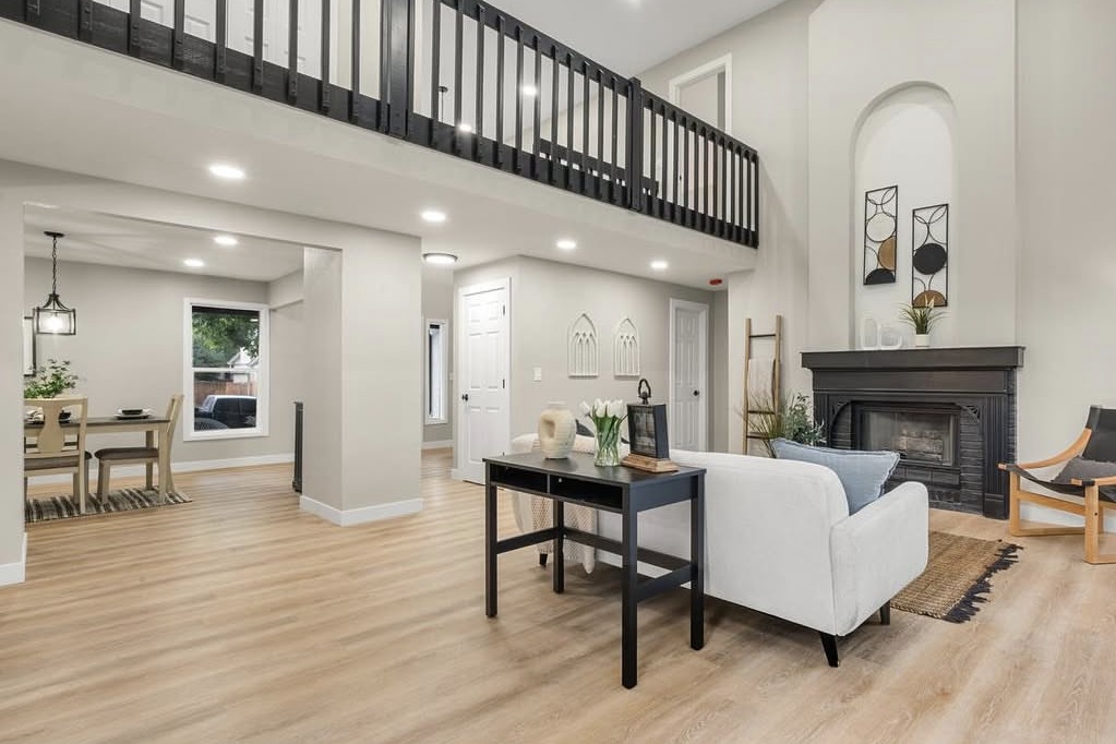 Two-story living room with a loft railing and black fireplace