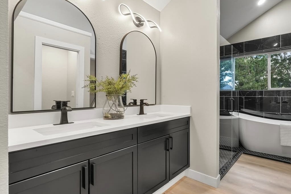 Primary bathroom with a black double vanity and freestanding tub